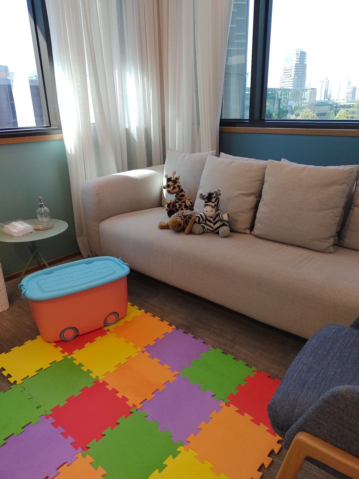 Sala de ludoterapia com tapete colorido e sofá